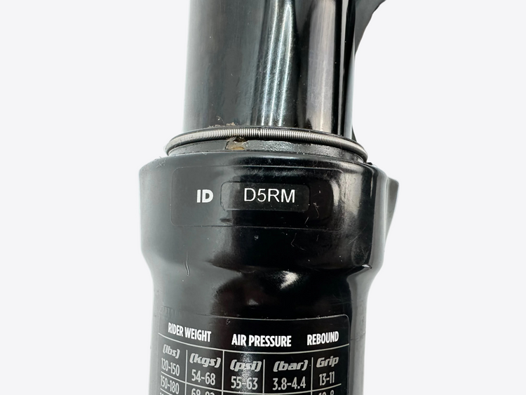 Close-up of a black suspension fork with 'D5RM' branding on a white background