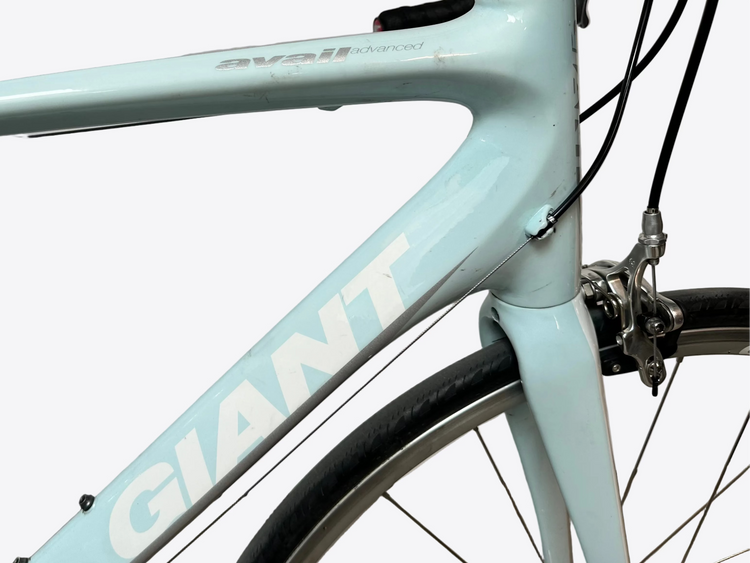 Light blue bicycle frame with 'Giant' branding against a white wall.