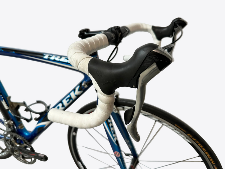 Close-up of a bicycle handlebar with white grips and black brake levers against a blurred background