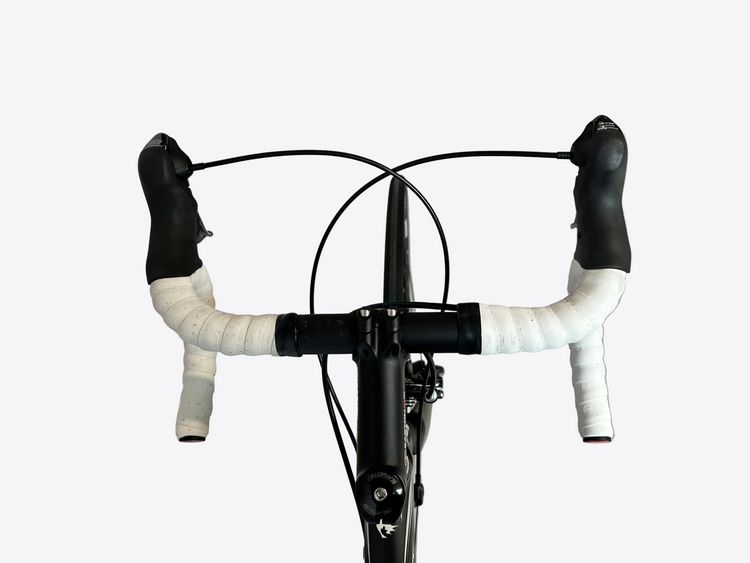 Bicycle handlebar with white grips and black bars on a concrete floor.