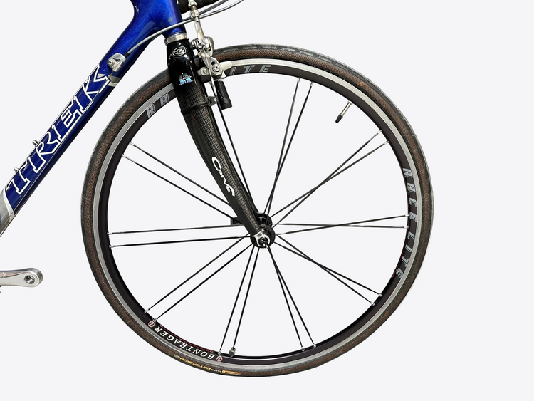 Bicycle wheel with 'Trek' branding against a gray brick wall.
