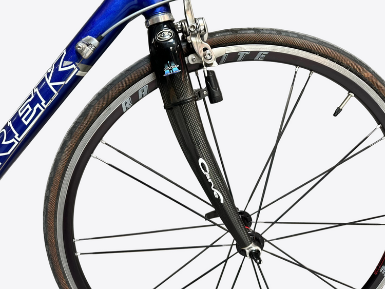 Close-up of a bicycle fork with 'Carve' branding against a gray brick wall.