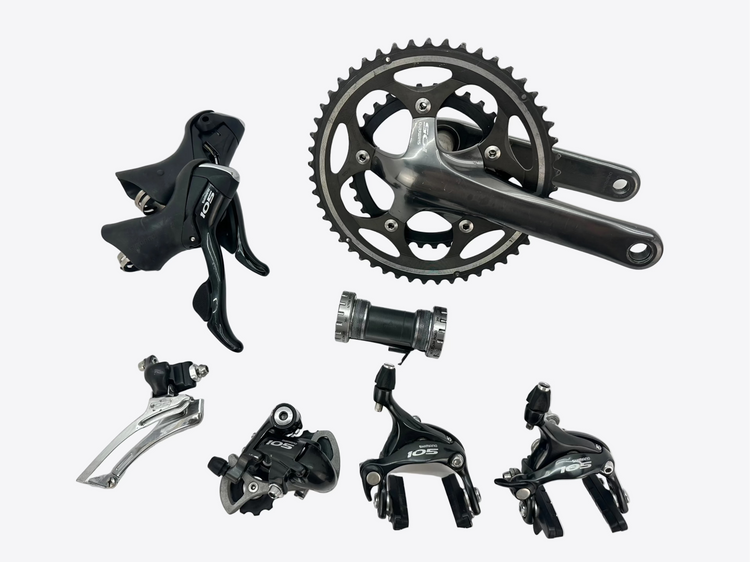 Collection of bicycle components including a chainring, derailleur, and brake levers on a white background.