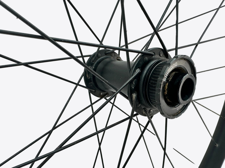 Close-up of a bicycle wheel hub with 'Shimano' branding on a light gray background