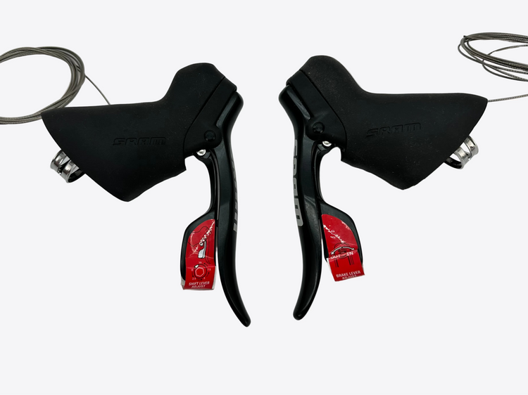 Pair of black bicycle shifters with red labels on a white background