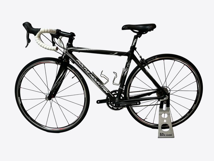 Black bicycle on a stand against a white wall