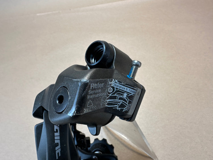 Close-up of a black metal clamp with branding on a beige background