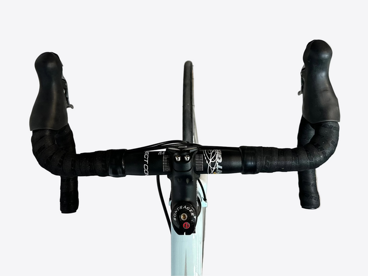 Bicycle handlebar with black grips and white frame on a concrete floor.
