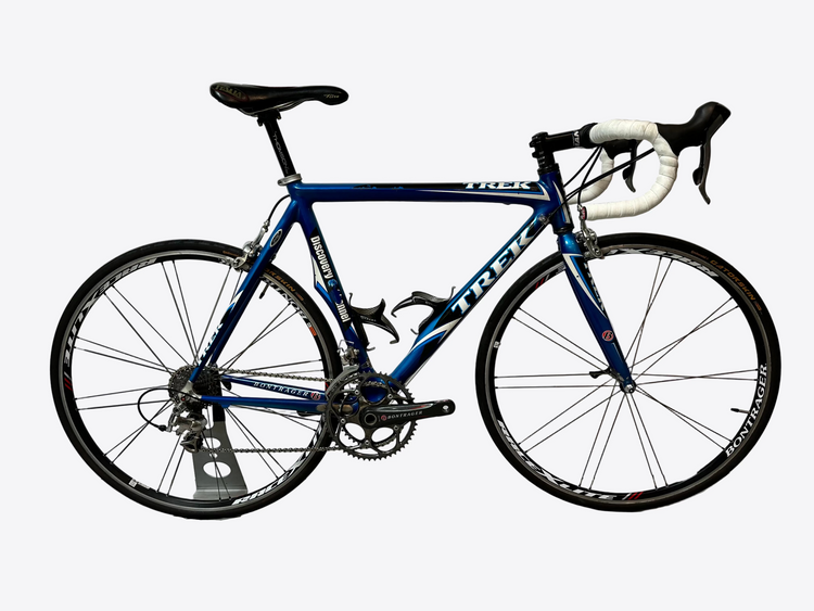 Blue Trek bicycle on a stand against a white background