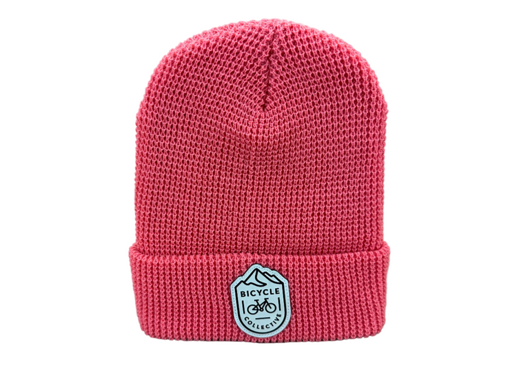 Pink knit beanie with a logo on a light gray background
