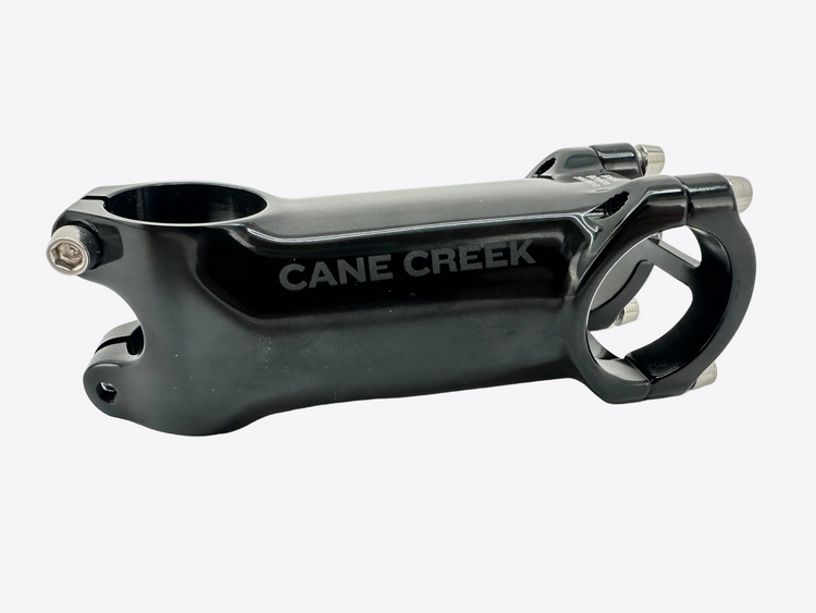 A black Cane Creek bicycle stem with silver bolts, shown on a light gray background.