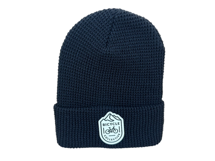 black beanie with a white logo on a light gray background