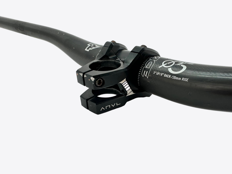 Close-up of a black bike handlebar with ANVL branding on a light gray background