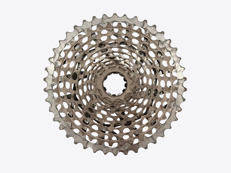 A silver bicycle cassette shown from a top-down view against a plain, light beige background.