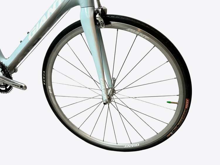 Close-up of a bicycle wheel with a white wall background
