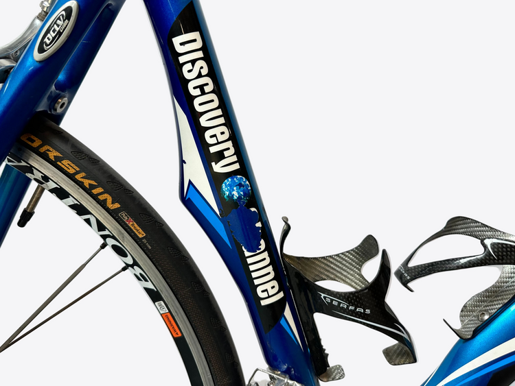 Close-up of a blue bicycle with 'Discovers' branding on a white background