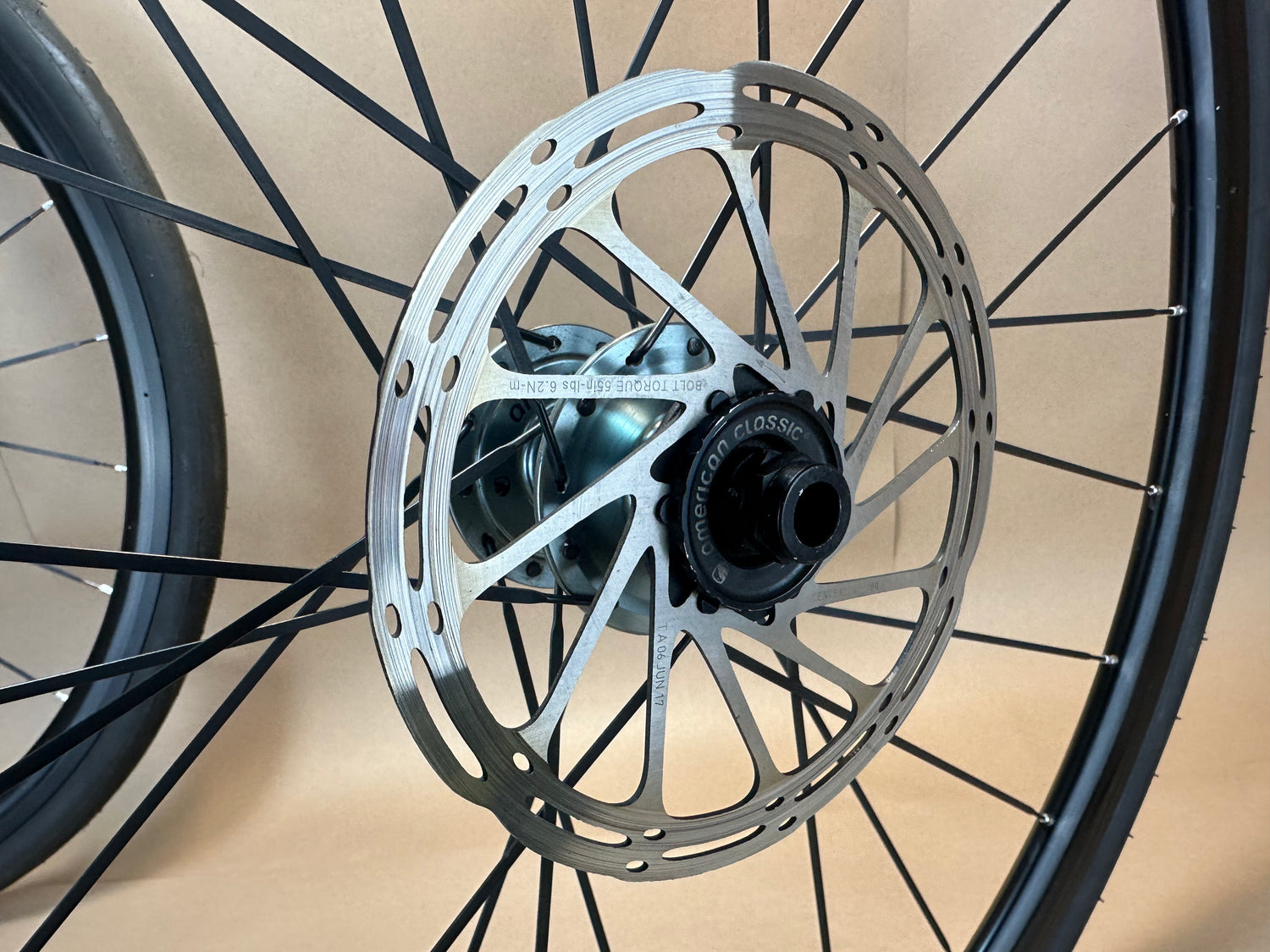 Close-up of a bicycle wheel with a disc brake rotor on a neutral background
