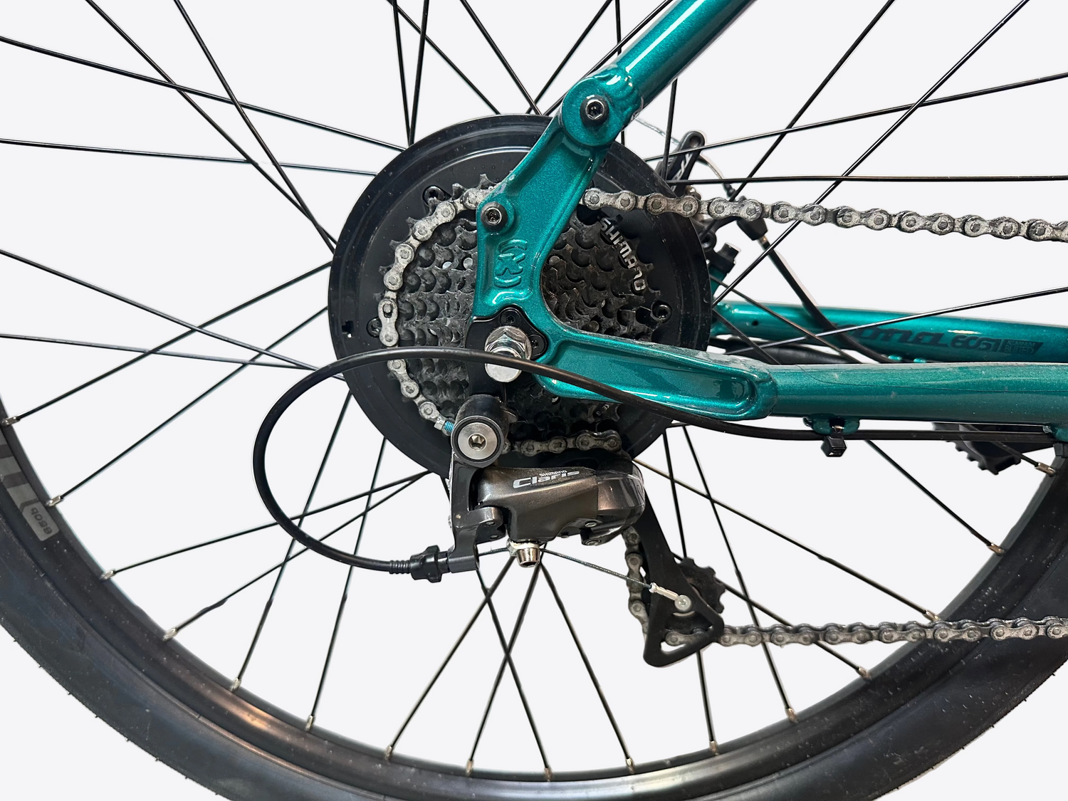 Close-up of a teal bicycle with gear and chain mechanism on a light background