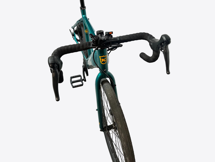Green bicycle leaning against a white wall in a garage.