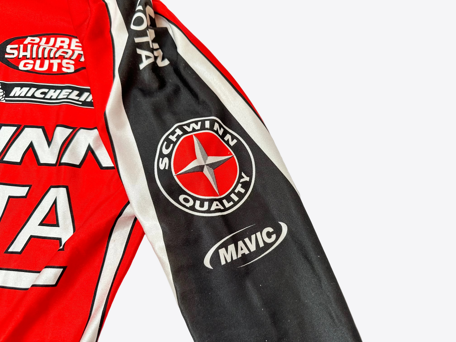 Close-up of red and black cycling pants with brand logos on a white background