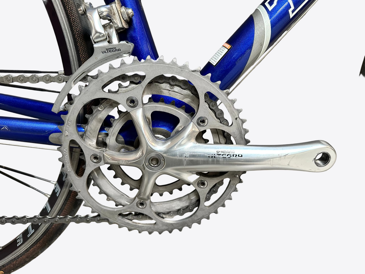 Close-up of a bicycle crankset with chainring against a gray tiled wall.
