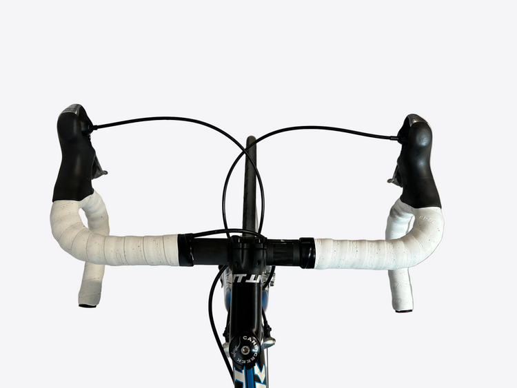 Bicycle handlebars with white grips on a concrete floor.