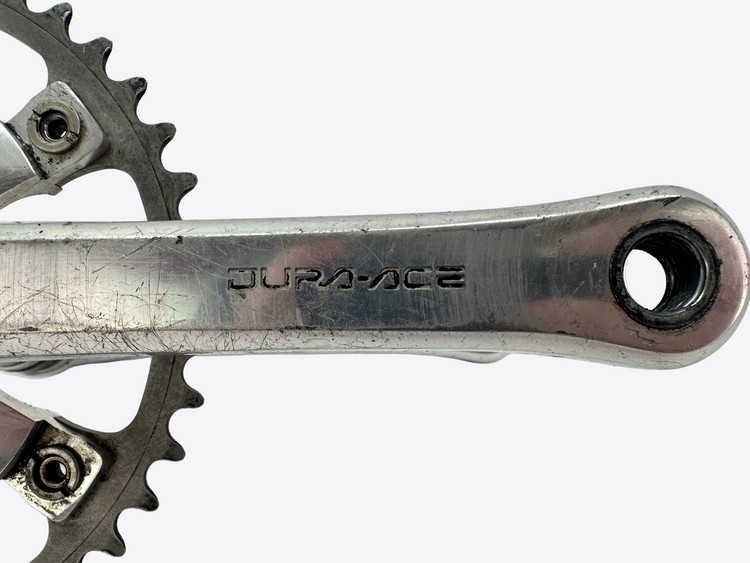 Close-up of a bicycle crankset with 'Dura-ACE' branding on a white background