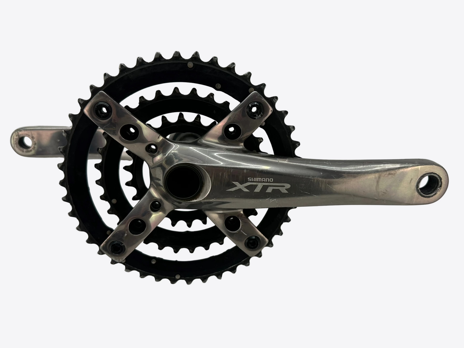 A Shimano XTR bicycle crankset with a silver aluminum crank arm, black chainrings, and black cleats, photographed on a light gray background.