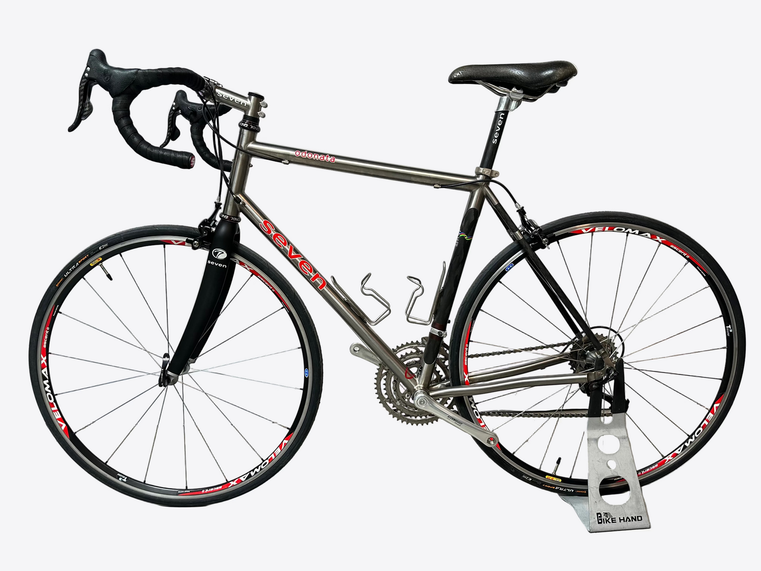 Seven bicycle on a stand against a white wall