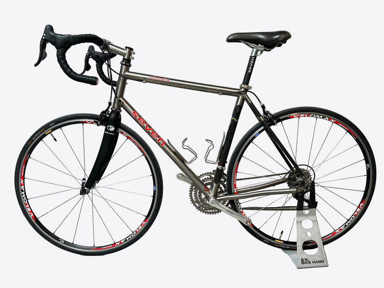 Seven bicycle on a stand against a white wall
