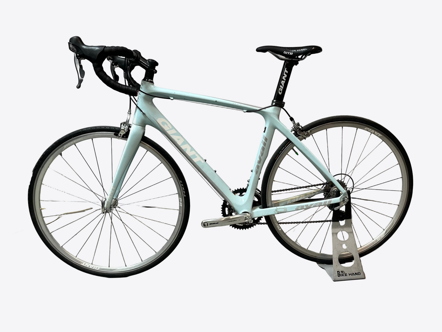 Light blue bicycle on a stand against a white wall