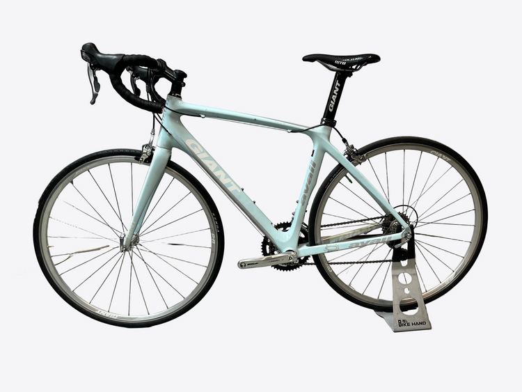 Light blue bicycle on a stand against a white wall