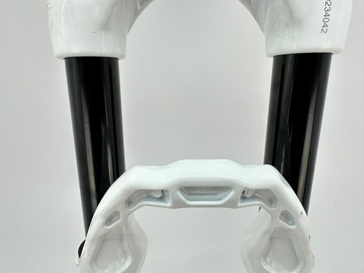 Close-up of bicycle forks with white plastic housing and black metal components on a light gray background.