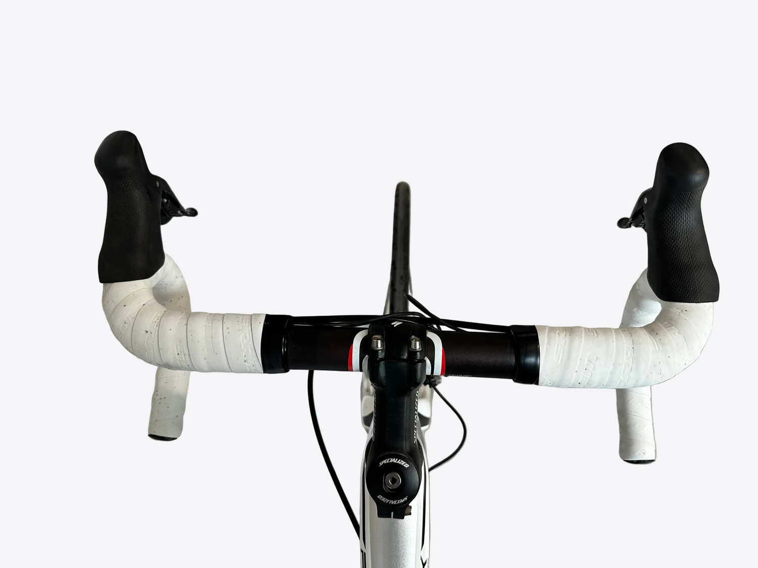 Close-up of a bicycle handlebar with white grips and black ends on a concrete floor.
