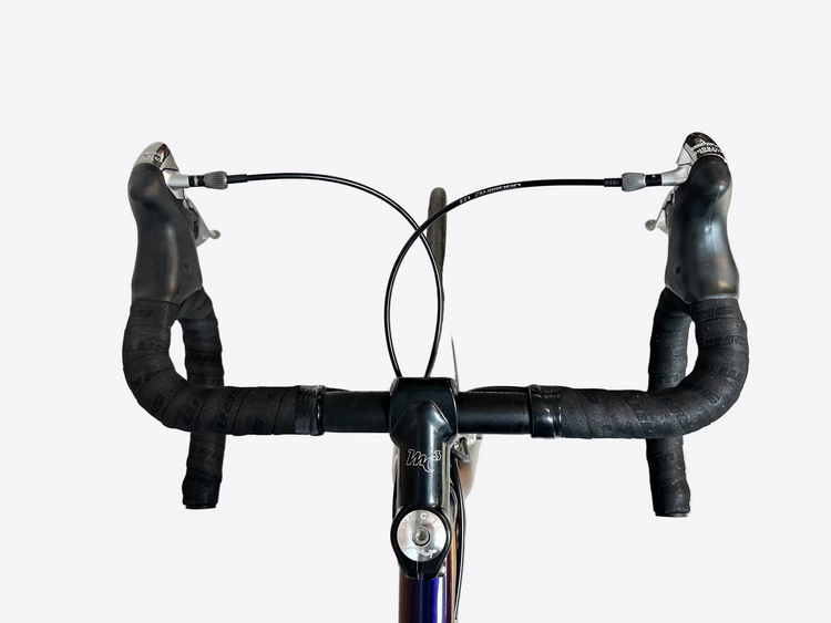 Close-up of a bicycle handlebar with black grips on a concrete floor.