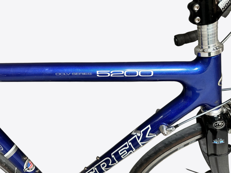 Blue Trek bicycle frame with '5200' model number against a gray tiled wall.