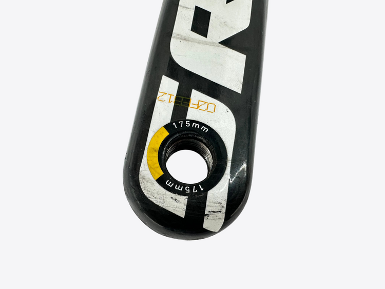 Close-up of a bicycle crank arm with brand and model details on a white background