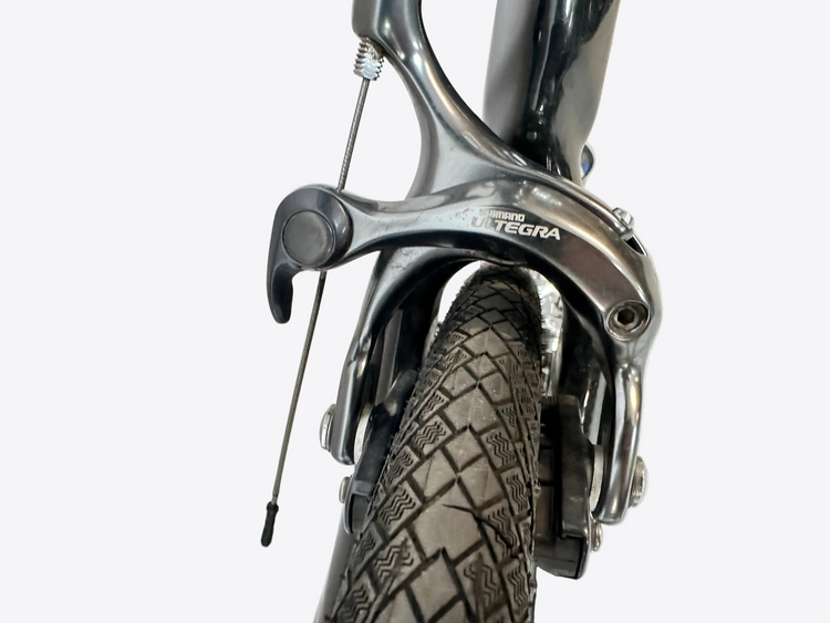 Close-up of a bicycle brake system with 'Shimano Ultegra' branding on a blurred background.