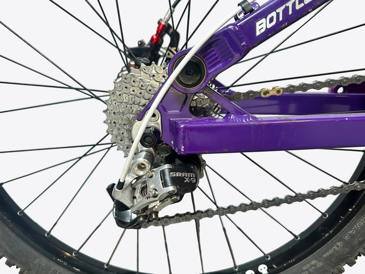 Close-up of a bicycle's gear system with a purple frame.