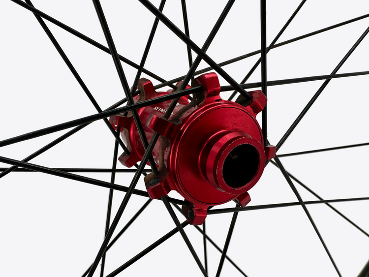 Close-up of a red bicycle hub with black spokes on a light gray background