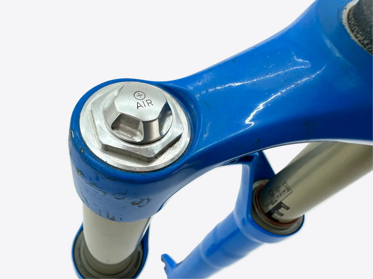 Close-up of a blue suspension fork with metal components on a white background