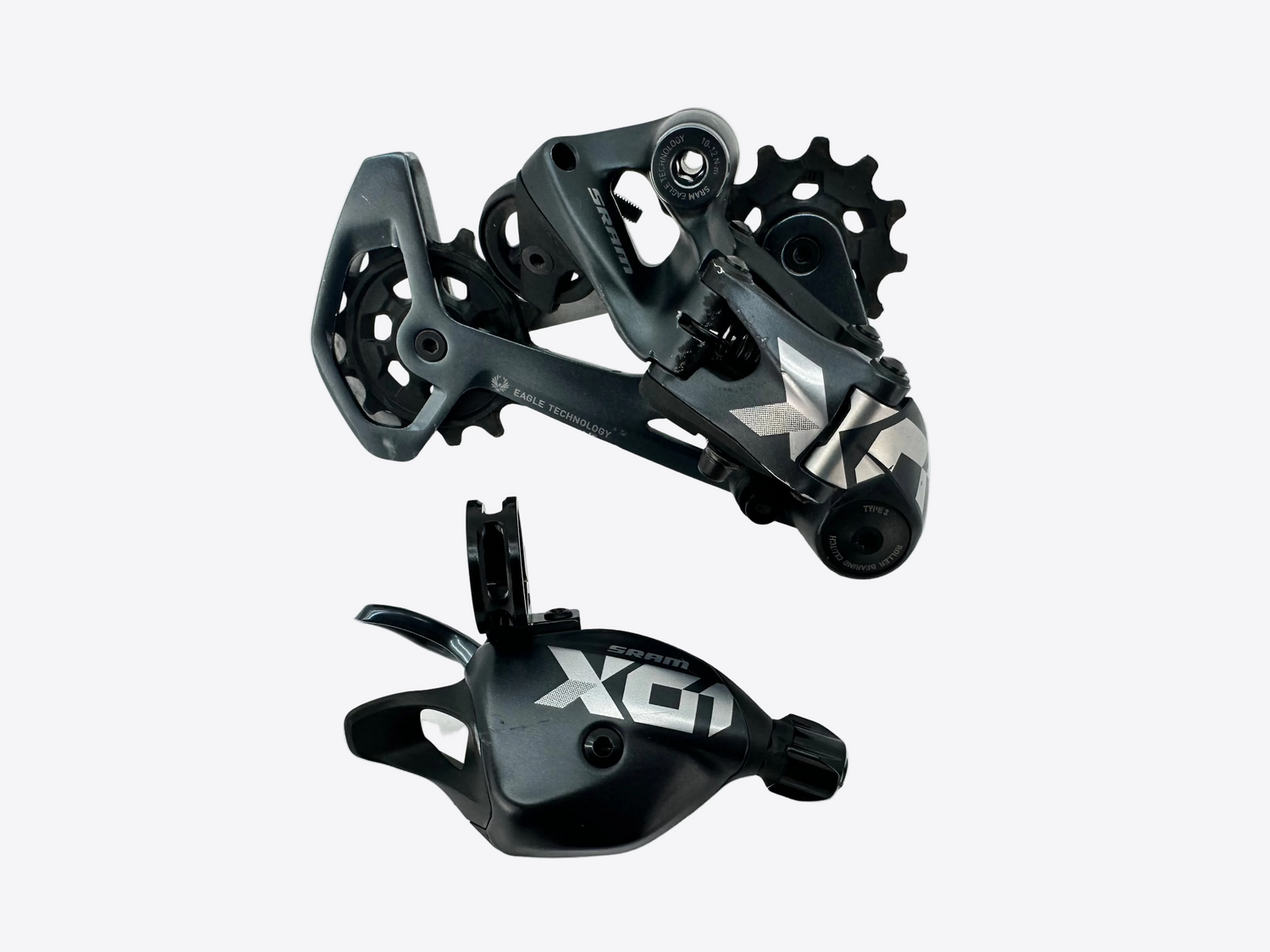 A black and silver X01 bicycle rear derailleur and matching cable guide shown on a light gray background.