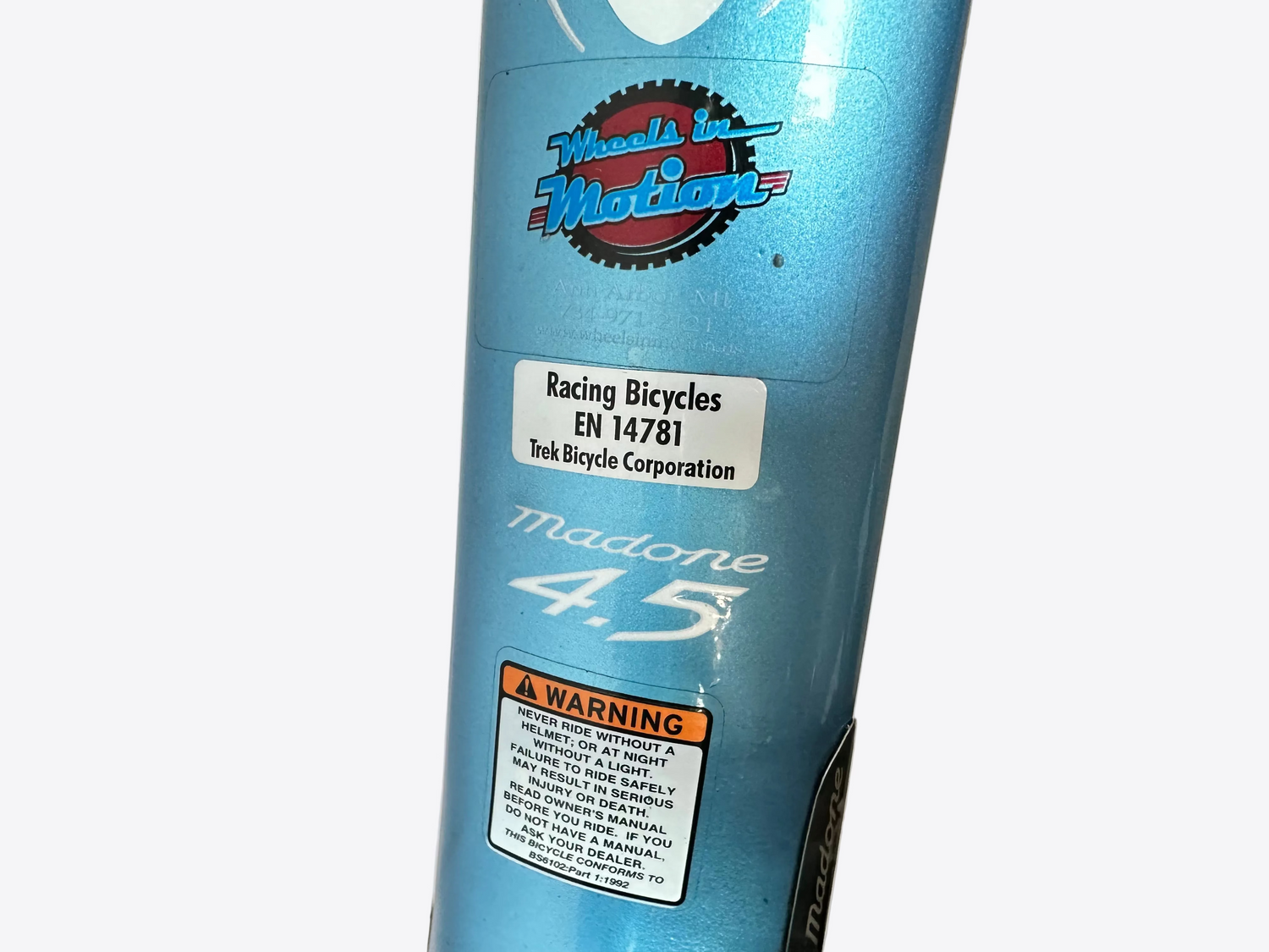 Blue bicycle rim with 'Madone' branding and tire attached on a concrete floor.