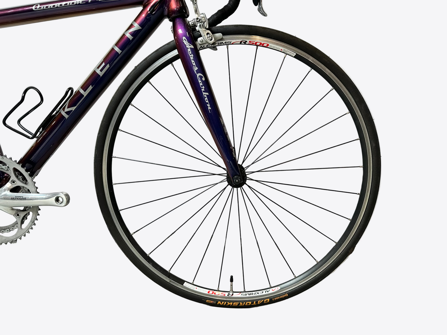Close-up of a bicycle wheel with a white wall in the background