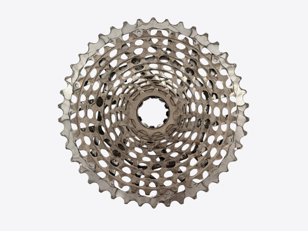 A silver bicycle cassette shown from a top-down view against a plain, light beige background.